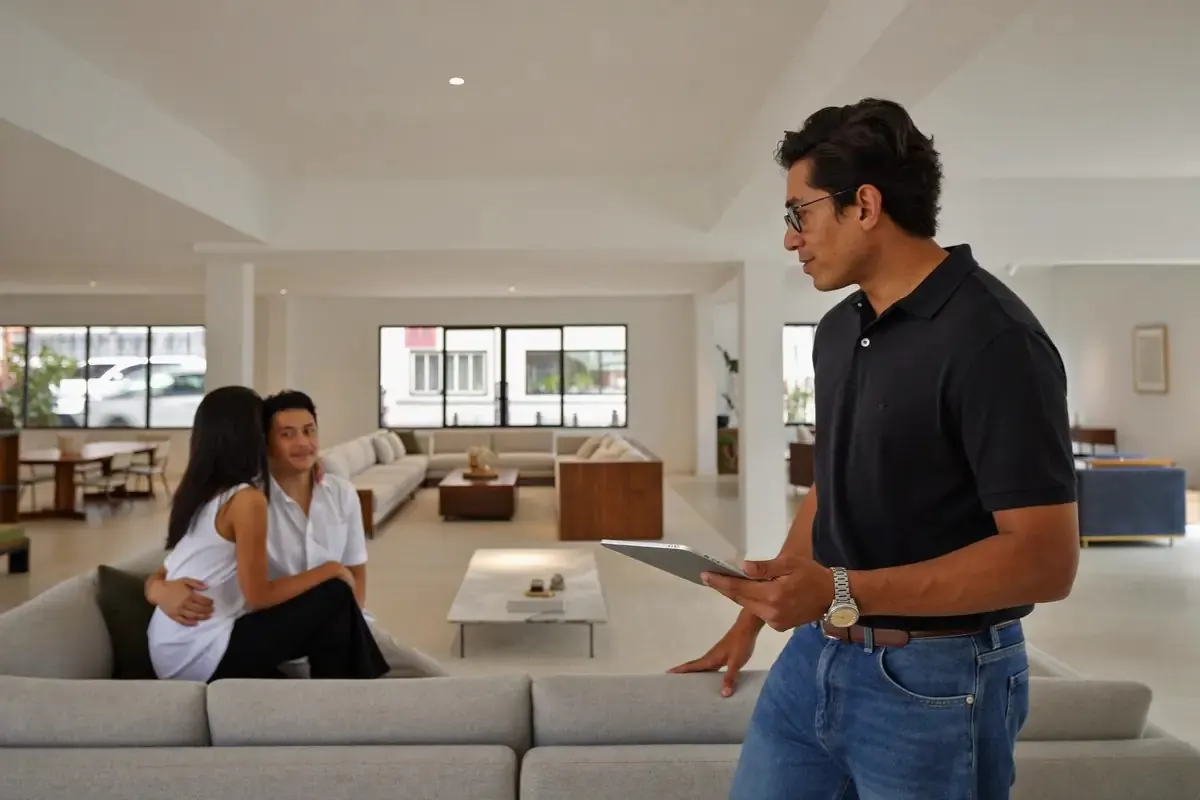 A furniture showroom owner with a tablet as customers look at a sofa